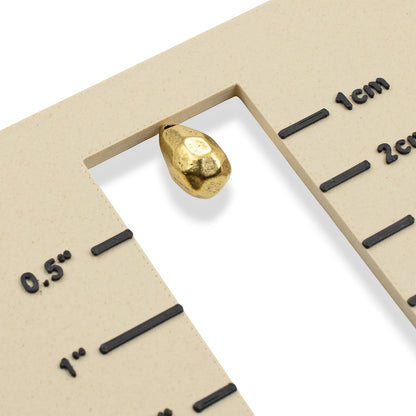 Hackberry Creek faceted drop bead in antique 24K gold-plated pewter shown on a measurement gauge for scale.