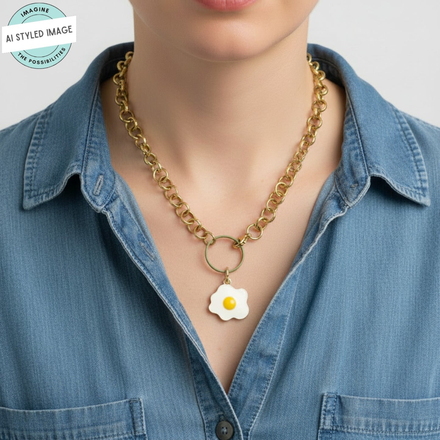 Hackberry Creek fried egg enamel charm pendant on a gold chain necklace worn by a person in a denim shirt.
