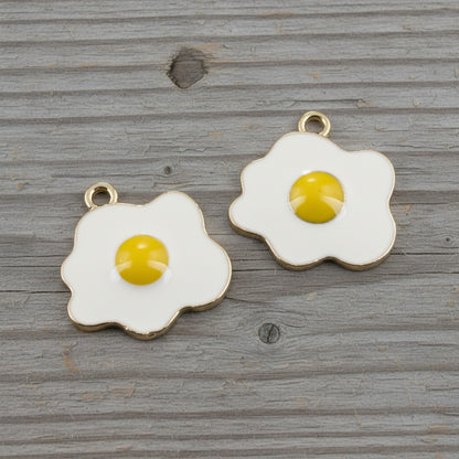 Hackberry Creek fried egg charms with white enamel and yellow yolk, featuring light gold metal edges for DIY jewelry.