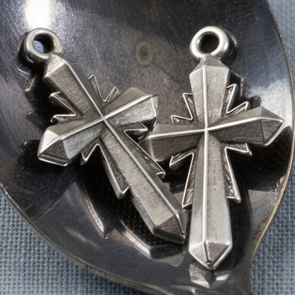 Two Hackberry Creek silver plated geometric cross pendants with an antique finish and faceted artisan design.