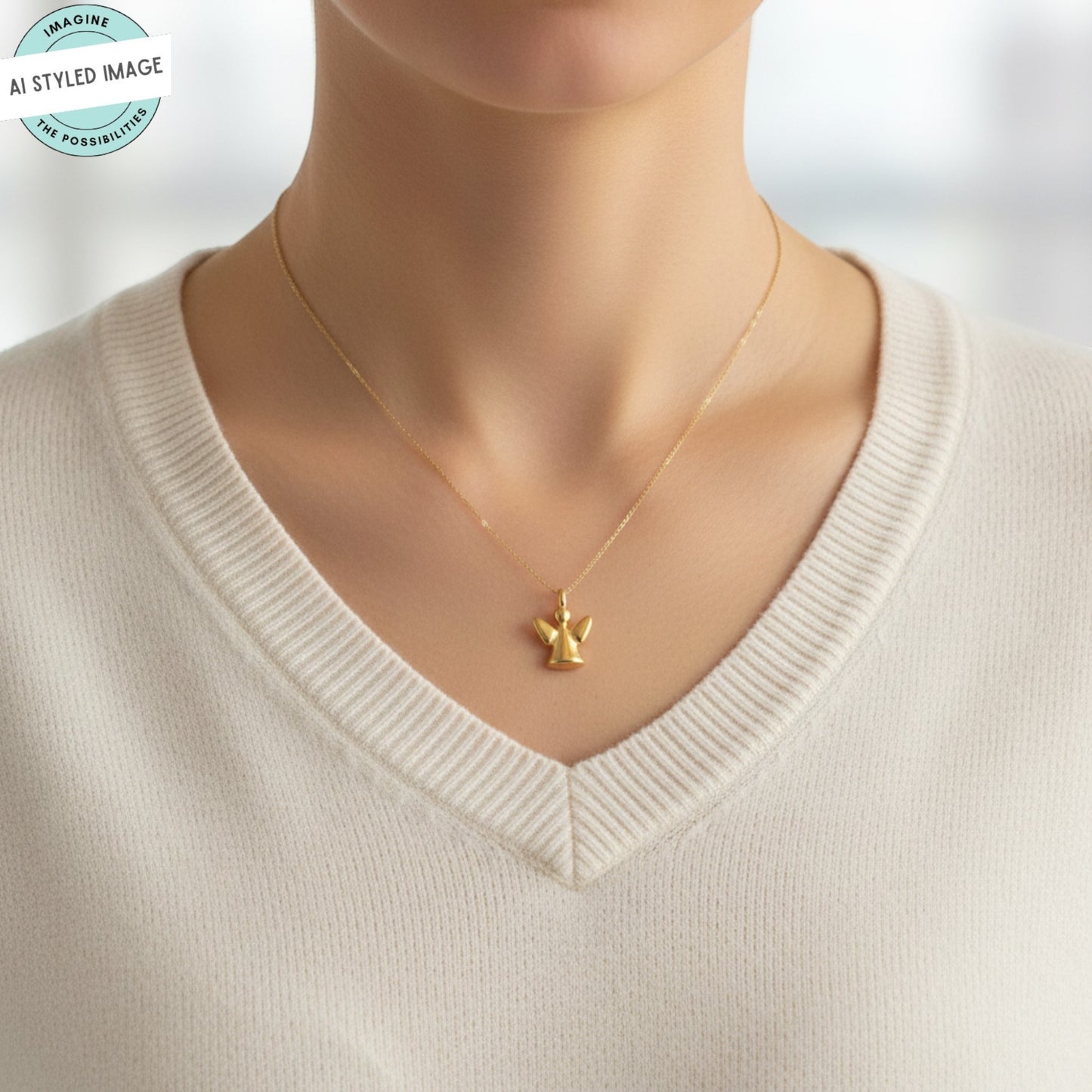 Hackberry Creek 24K gold-plated guardian angel charm pendant worn on a delicate chain by a person in a white sweater.