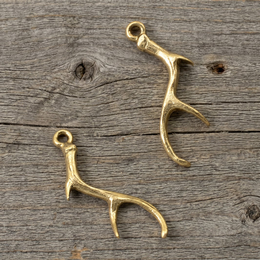 Hackberry Creek Nunn Design gold plated pewter antler charms for jewelry making on a rustic wood background.