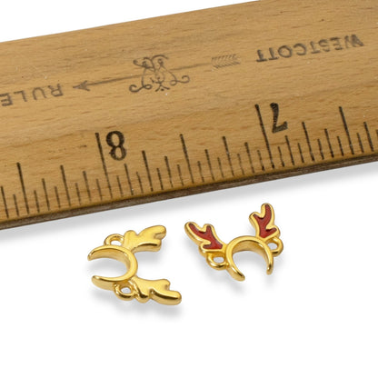 Hackberry Creek 24k gold plated antler jewelry connectors with red enamel details next to a wooden ruler for scale.