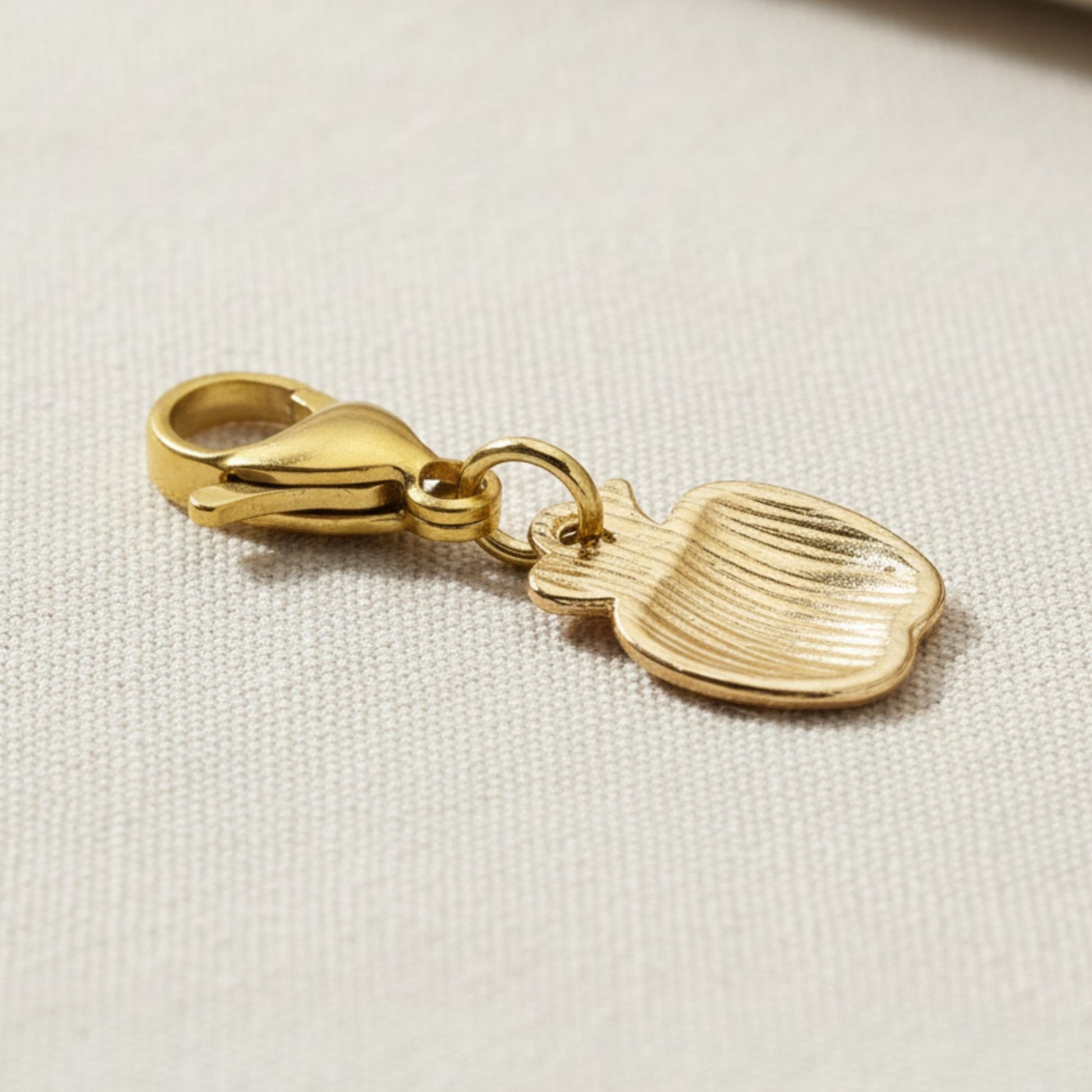 Hackberry Creek gold-plated brass apple charm showing the plain textured reverse side with a secure lobster clasp.
