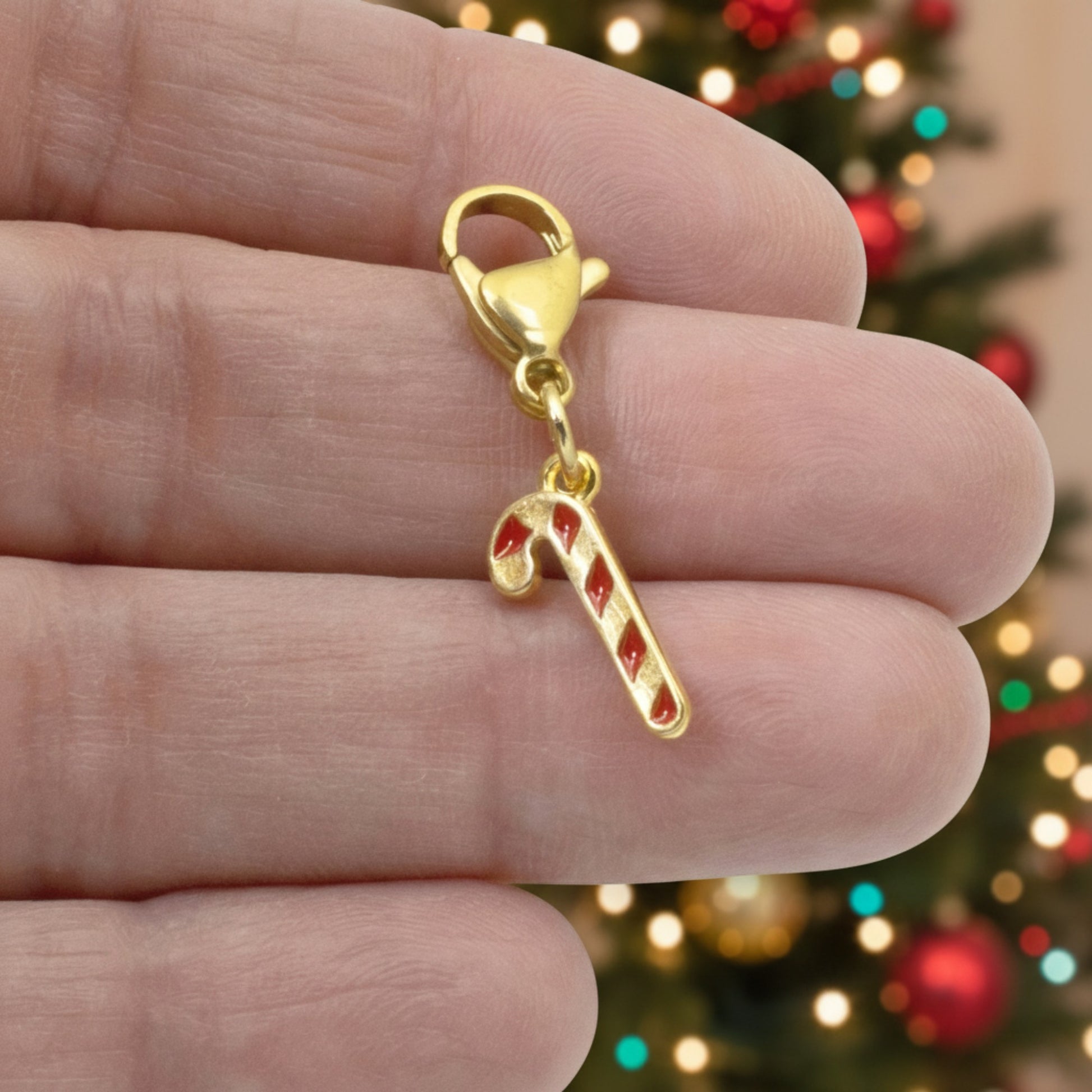 Hackberry Creek 24k gold-plated candy cane charm with red enamel stripes and a secure lobster clasp for bracelets.