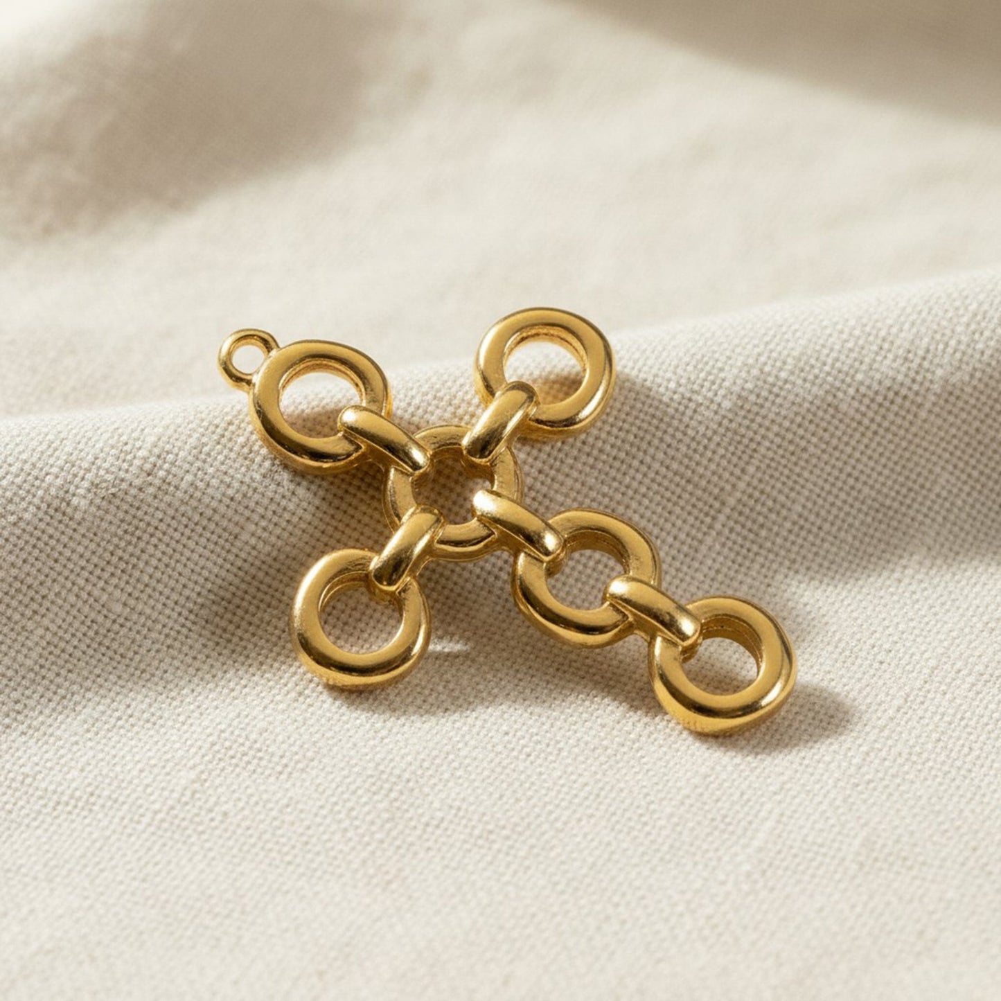 Hackberry Creek 24K gold plated cross pendant featuring an architectural open chain-link design on textured fabric.