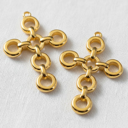 Hackberry Creek 24K gold plated open chain link cross pendants with multiple connection points on white fabric.