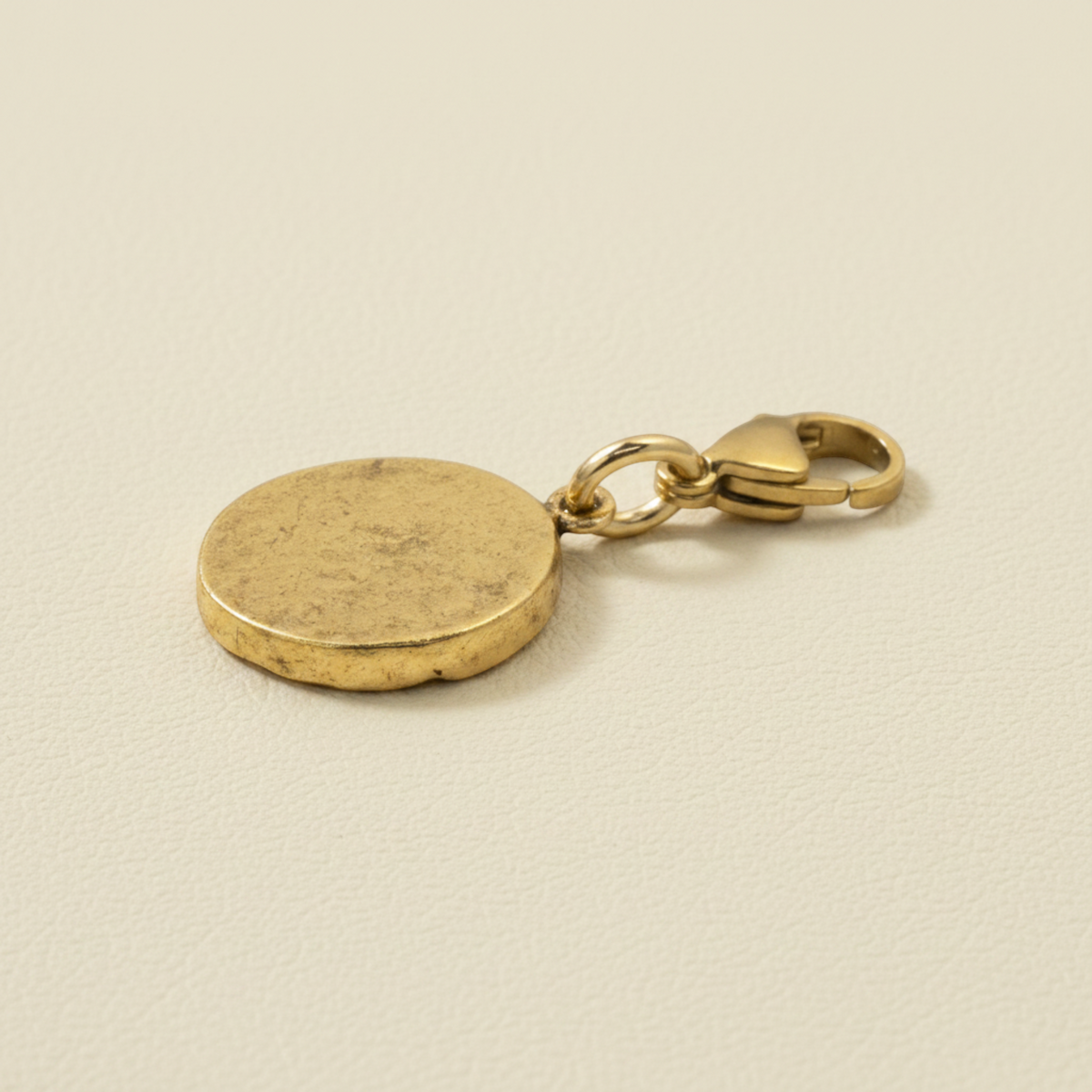 Hackberry Creek gold crown charm with an antique finish and a secure lobster clasp on a neutral textured background.