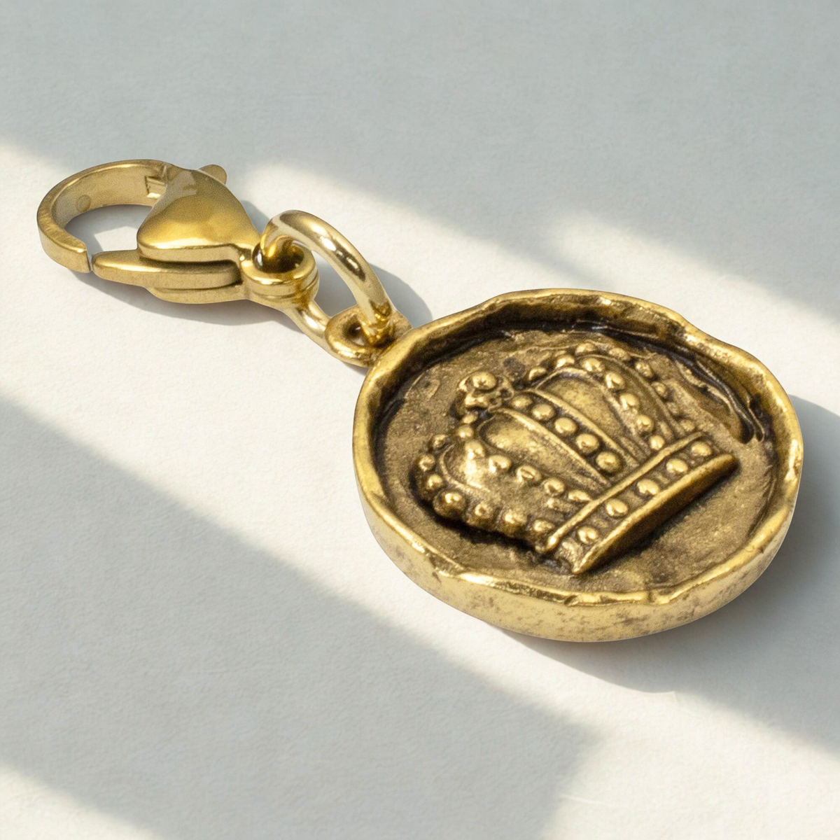 Hackberry Creek antique gold crown charm with a secure lobster clasp, featuring an intricate raised regal design.