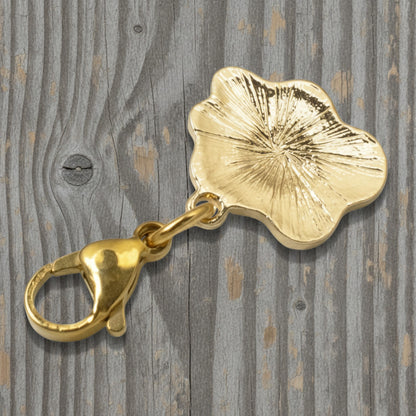 Hackberry Creek gold-plated egg charm with a textured back, featuring a secure lobster clasp on a wooden surface.