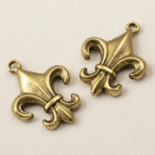 Two Hackberry Creek gold fleur de lis charms with an antique finish and intricate double-sided detailing.