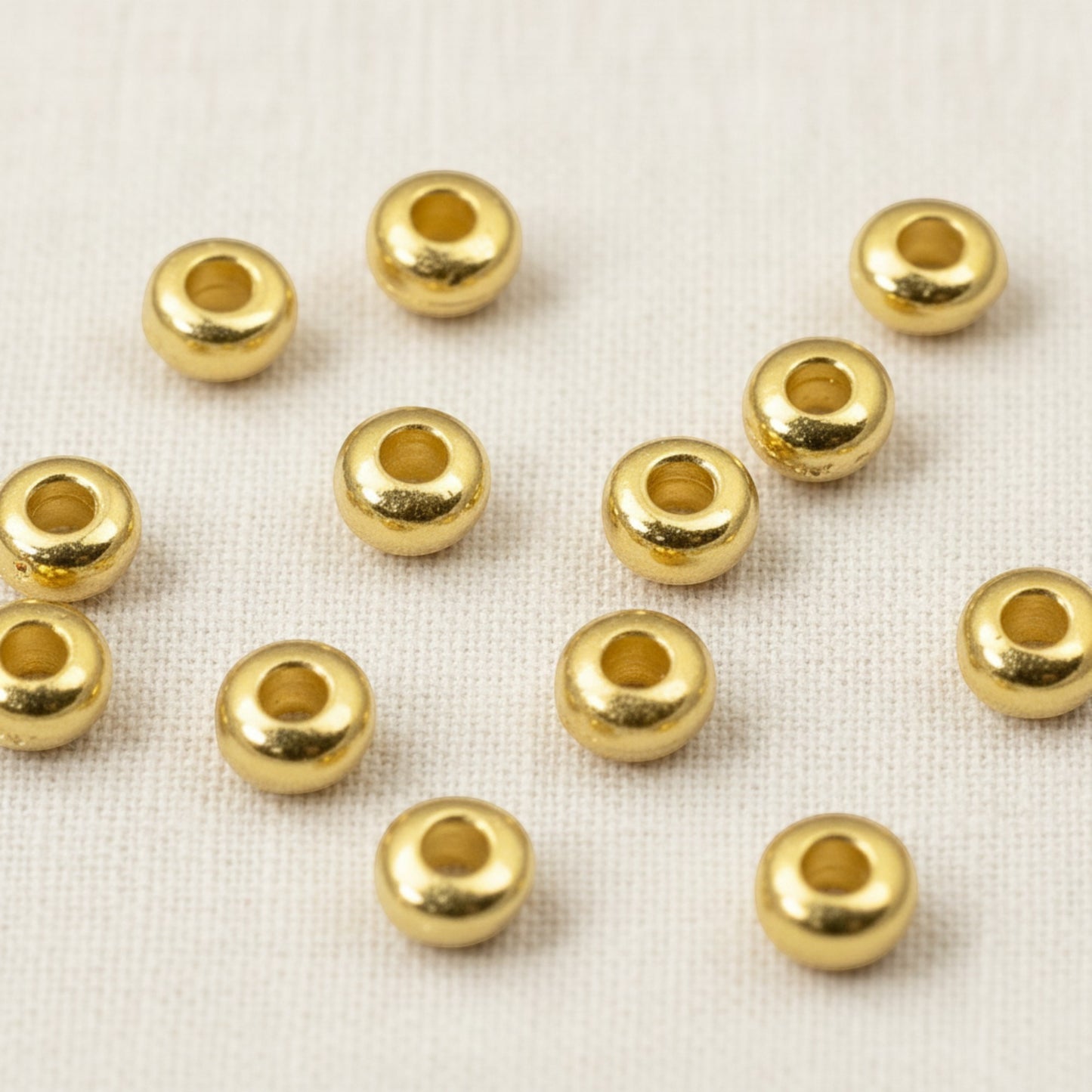 Hackberry Creek 3mm gold heishi disc spacer beads made of 24K-plated pewter. Smooth, round beads for jewelry making.
