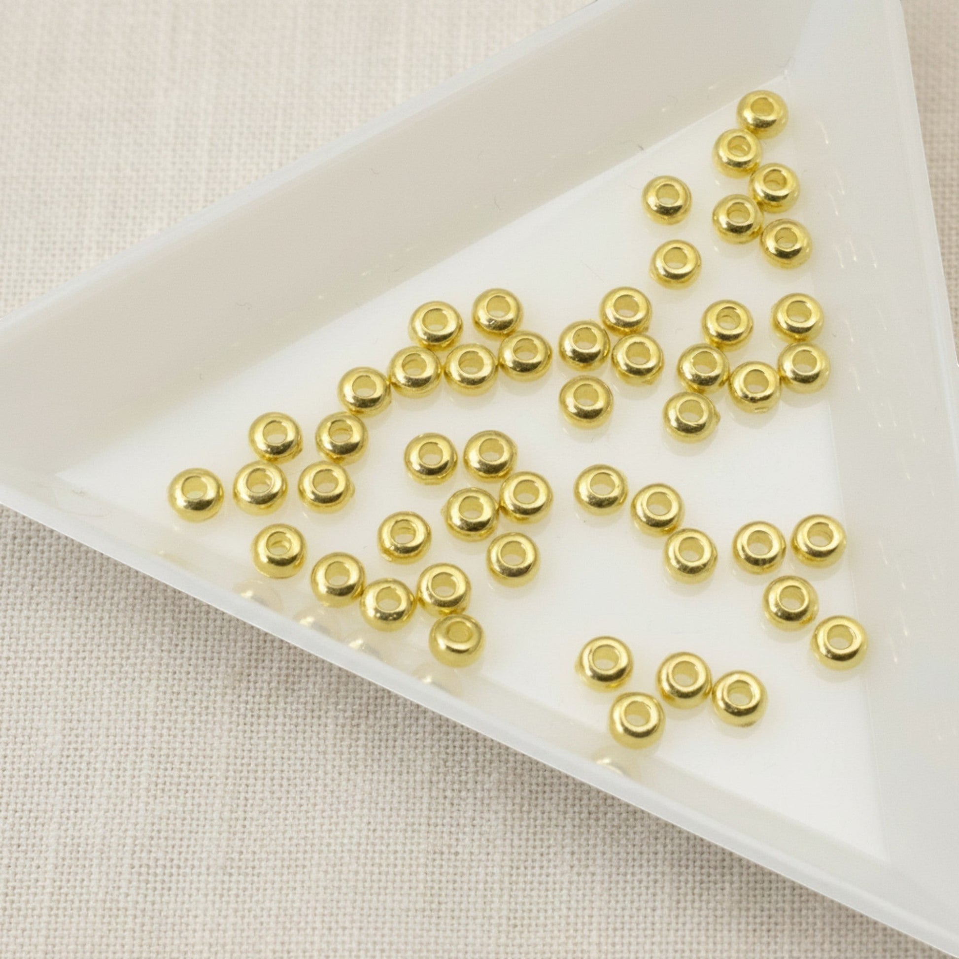 Hackberry Creek 3mm gold heishi disc spacer beads made of 24K-plated pewter. Smooth, bright gold finish.