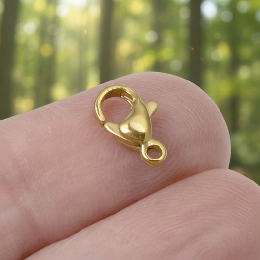 Hackberry Creek small 18k gold-plated stainless steel lobster claw clasp held on a finger for scale