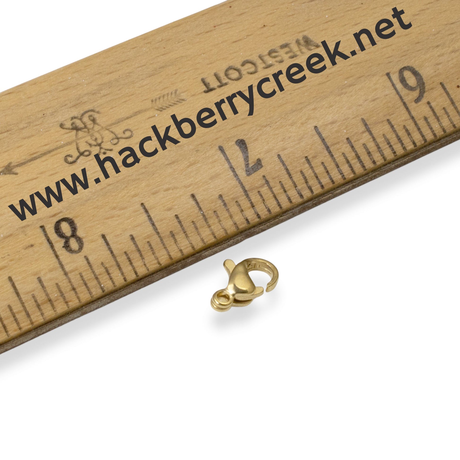 Hackberry Creek small 7x10mm gold-plated stainless steel lobster claw clasp next to a ruler for scale