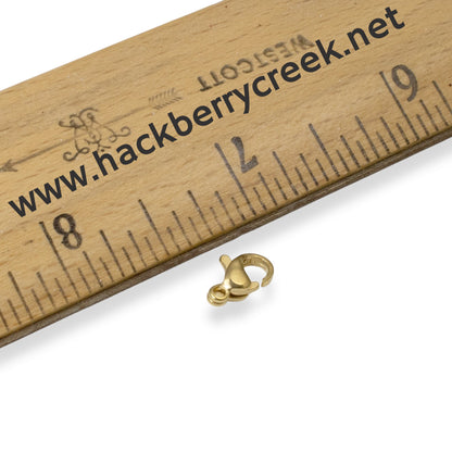 Hackberry Creek small 7x10mm gold-plated stainless steel lobster claw clasp next to a ruler for scale