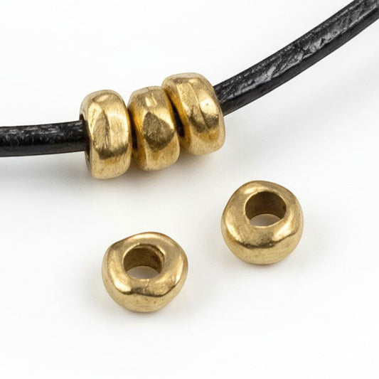 Hackberry Creek 24k gold plated pewter nugget spacer beads on a black leather cord for jewelry making.