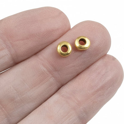 Hackberry Creek 24k gold plated pewter nugget spacer beads with organic shape held on fingertips.