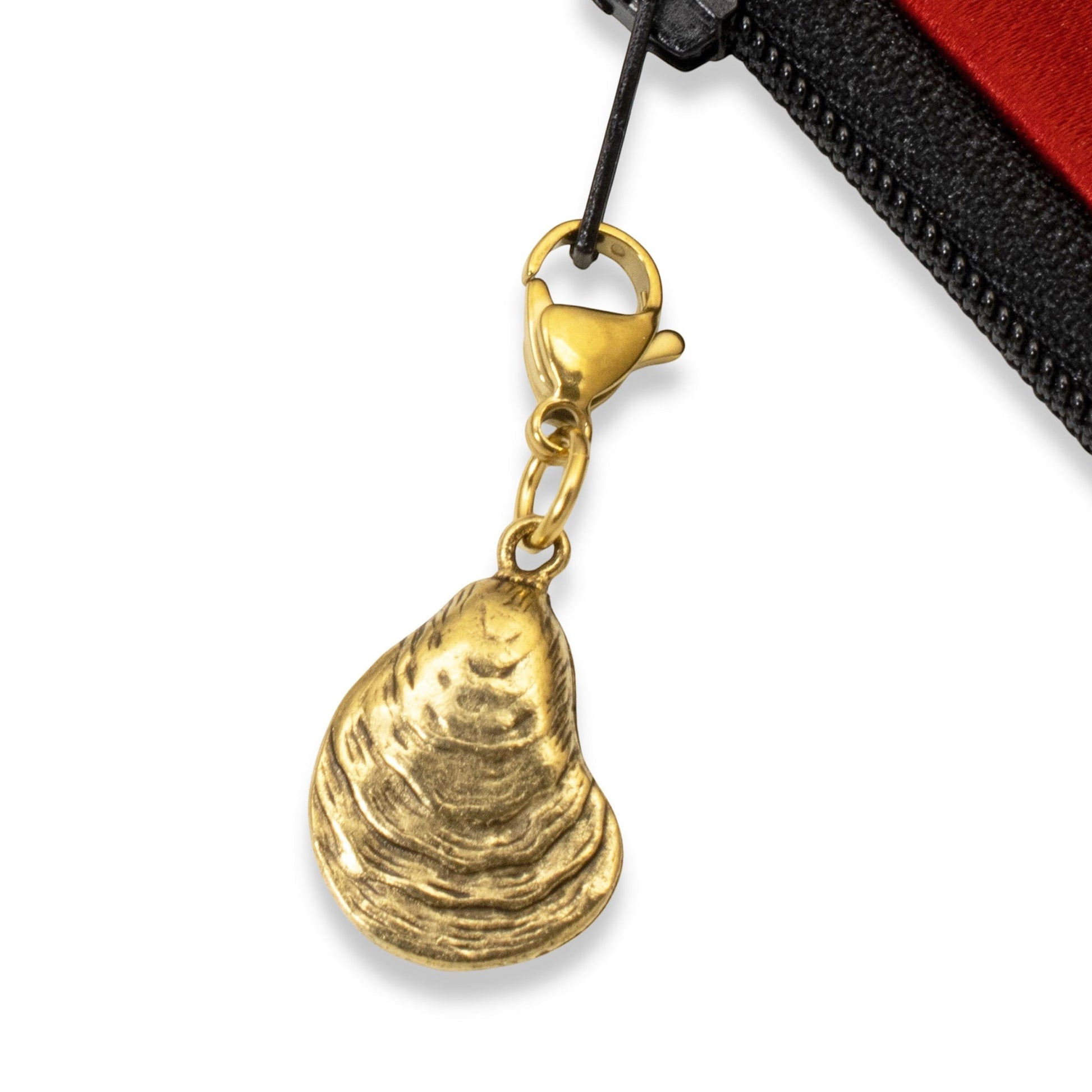 Hackberry Creek 24k gold-plated oyster shell charm with a stainless steel lobster clasp attached to a bag zipper.