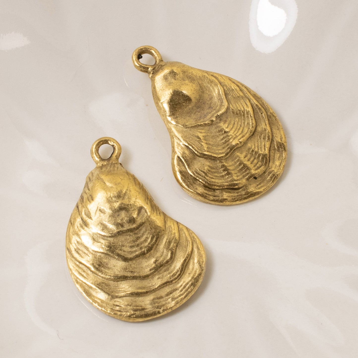 Hackberry Creek set of two 24k gold plated oyster shell charms with an antiqued finish for coastal jewelry making.