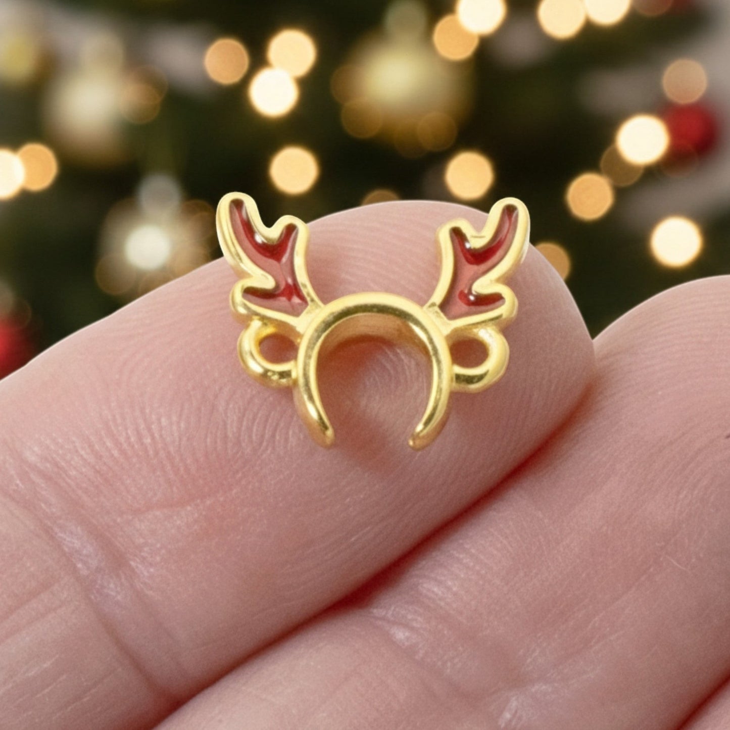 Hackberry Creek 24k gold plated reindeer antler jewelry connector with red enamel details held against a tree background
