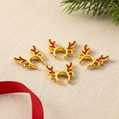 Hackberry Creek 24k gold plated reindeer antler jewelry connectors with red enamel details on a textured surface.