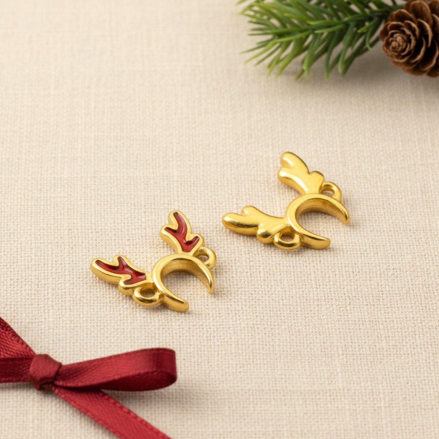 Hackberry Creek 24k gold-plated reindeer antler jewelry connectors with red enamel details on a festive background.