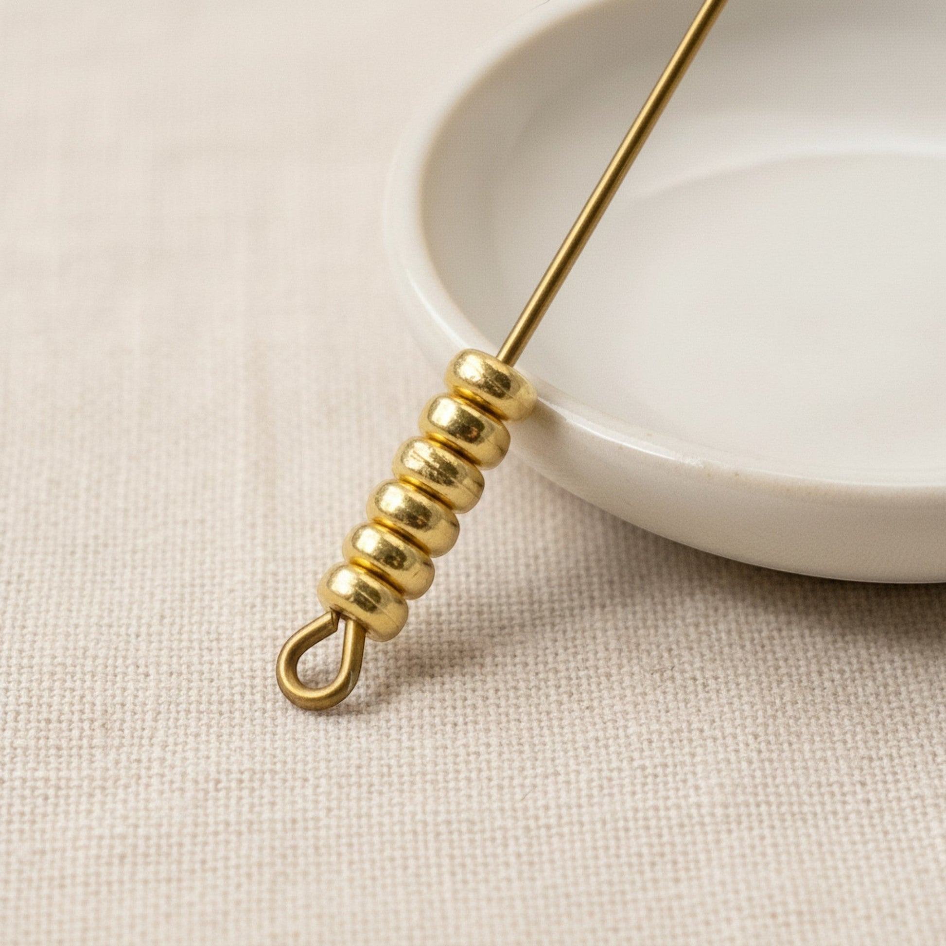 Hackberry Creek 3mm gold heishi disc spacer beads made of 24K-plated pewter. Smooth, round beads on a jewelry wire.