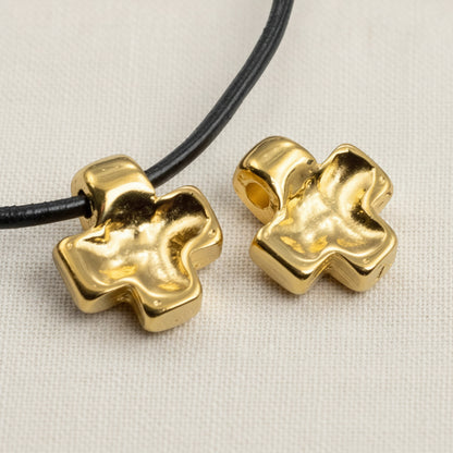 Hackberry Creek 24K gold plated cross pendants with textured wave pattern on a white fabric background