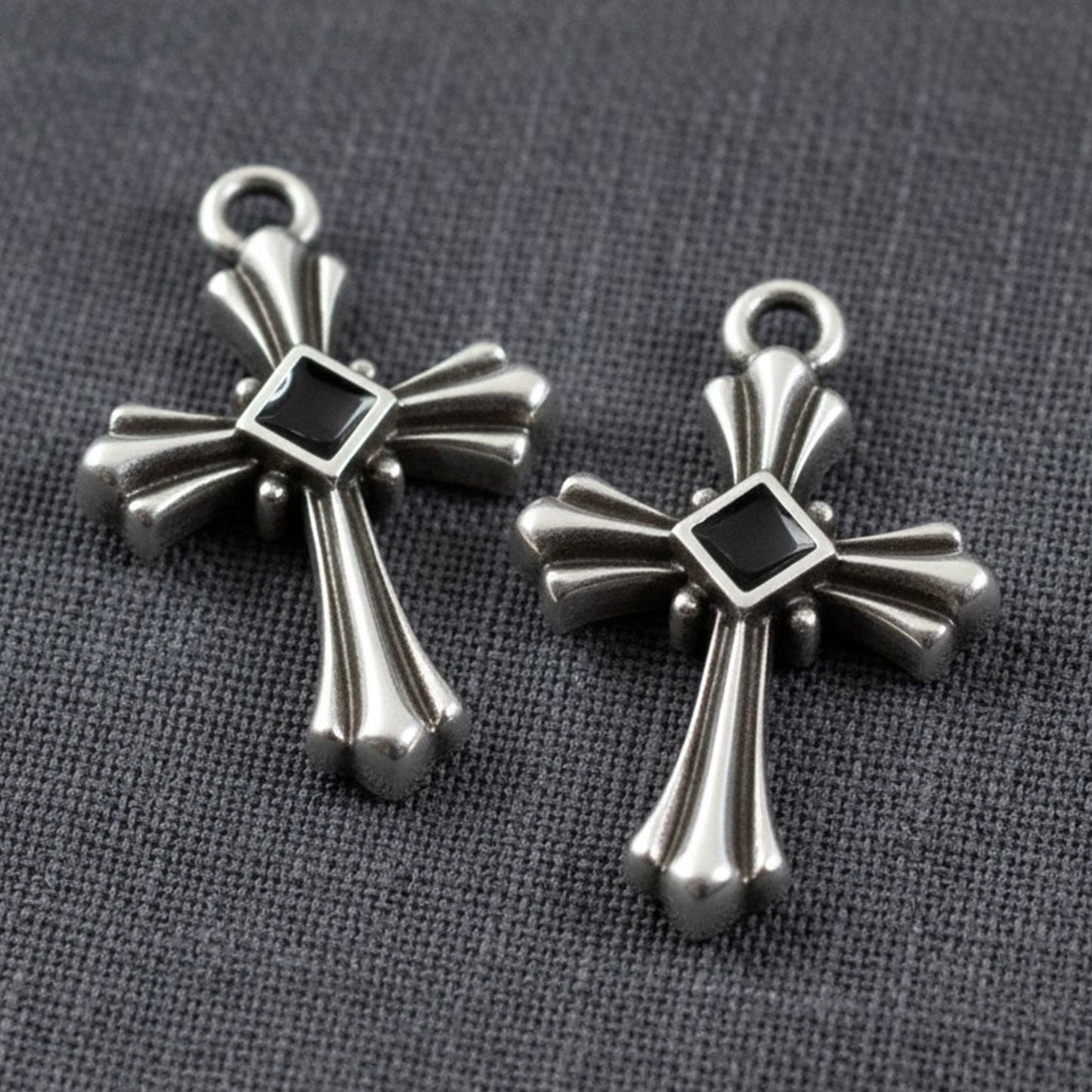 Hackberry Creek silver plated gothic cross pendants with black enamel center accents on a grey fabric background