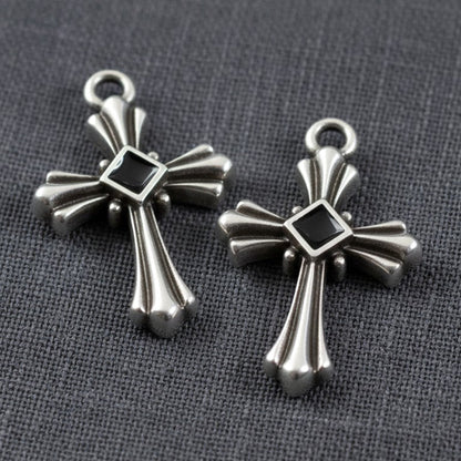 Hackberry Creek silver plated gothic cross pendants with black enamel center accents on a grey fabric background
