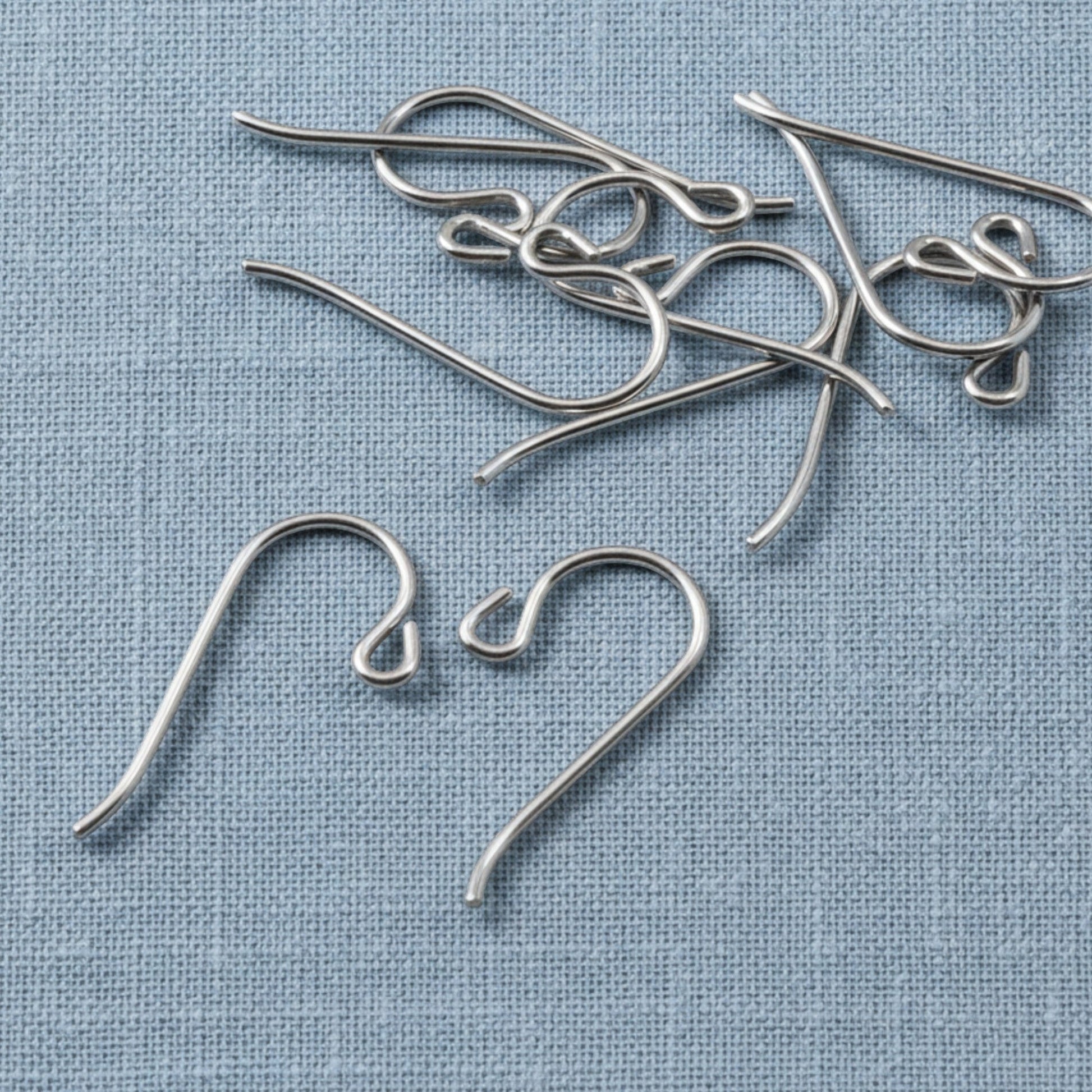 Hackberry Creek hypoallergenic gray niobium French hook ear wires with small loops on a blue fabric background.