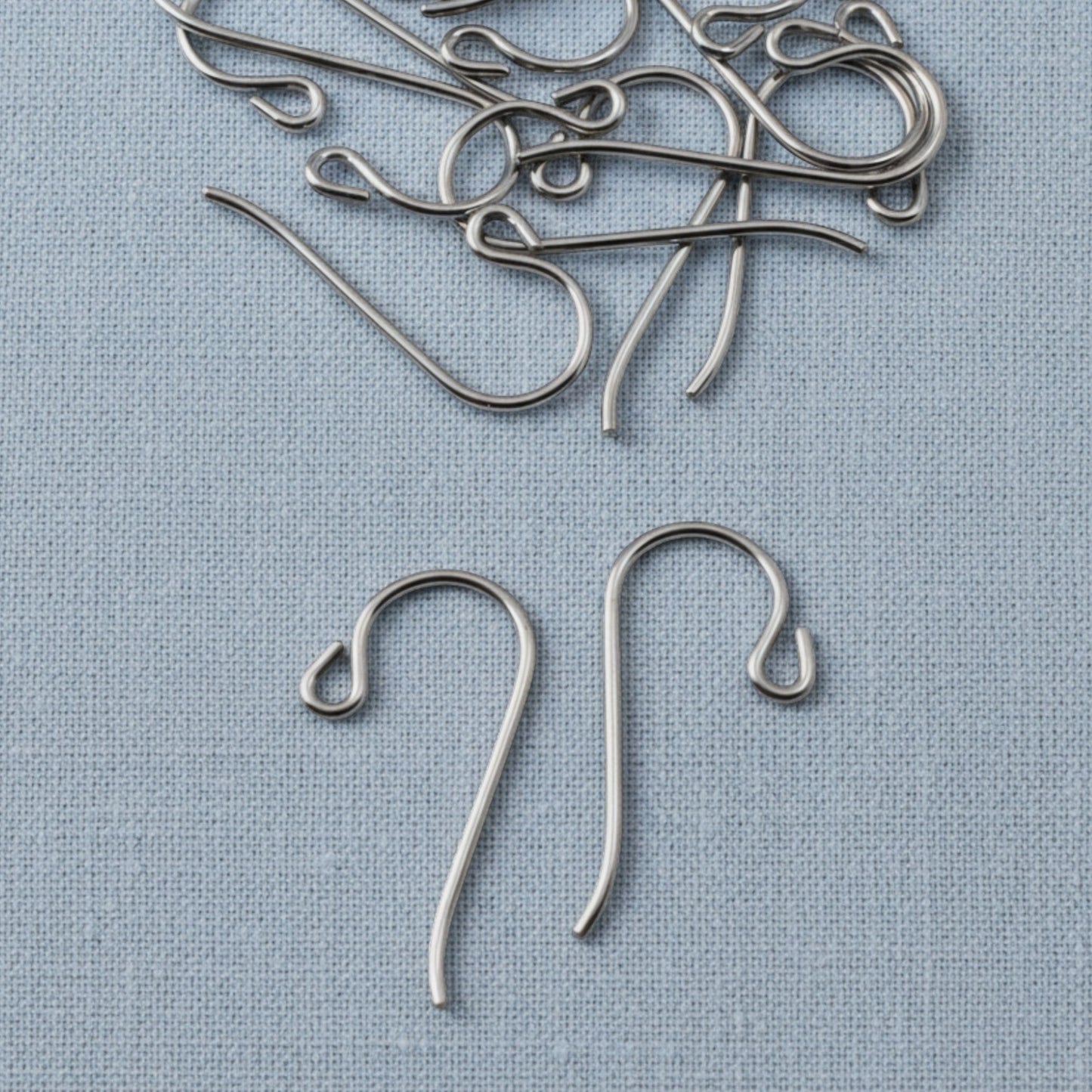 Hackberry Creek hypoallergenic gray niobium French hook ear wires with small loops on a light blue fabric background.