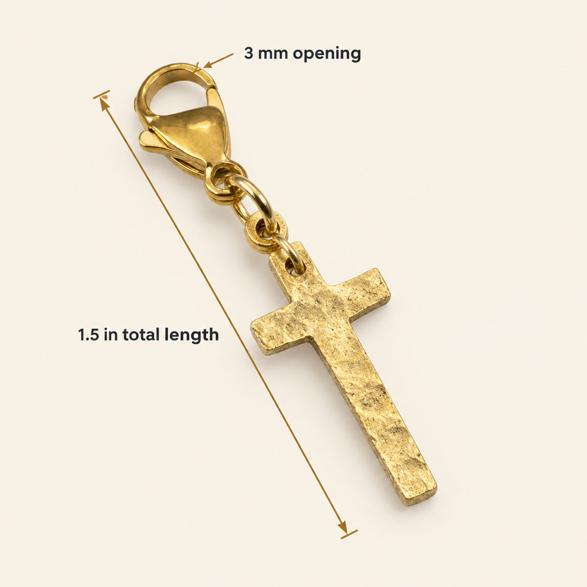 Hackberry Creek gold cross charm with hammered texture and lobster clasp on a light background