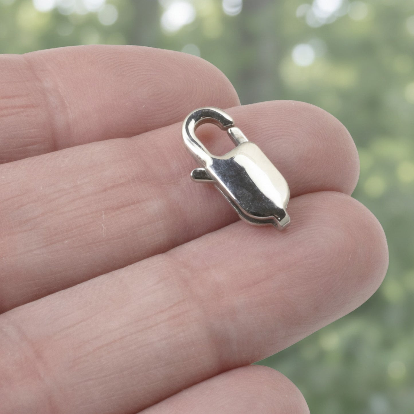 Hackberry Creek large oval silver stainless steel lobster claw clasp held between fingers for jewelry making