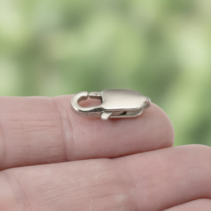 Hackberry Creek large oval silver stainless steel lobster claw clasp held on a finger for jewelry making