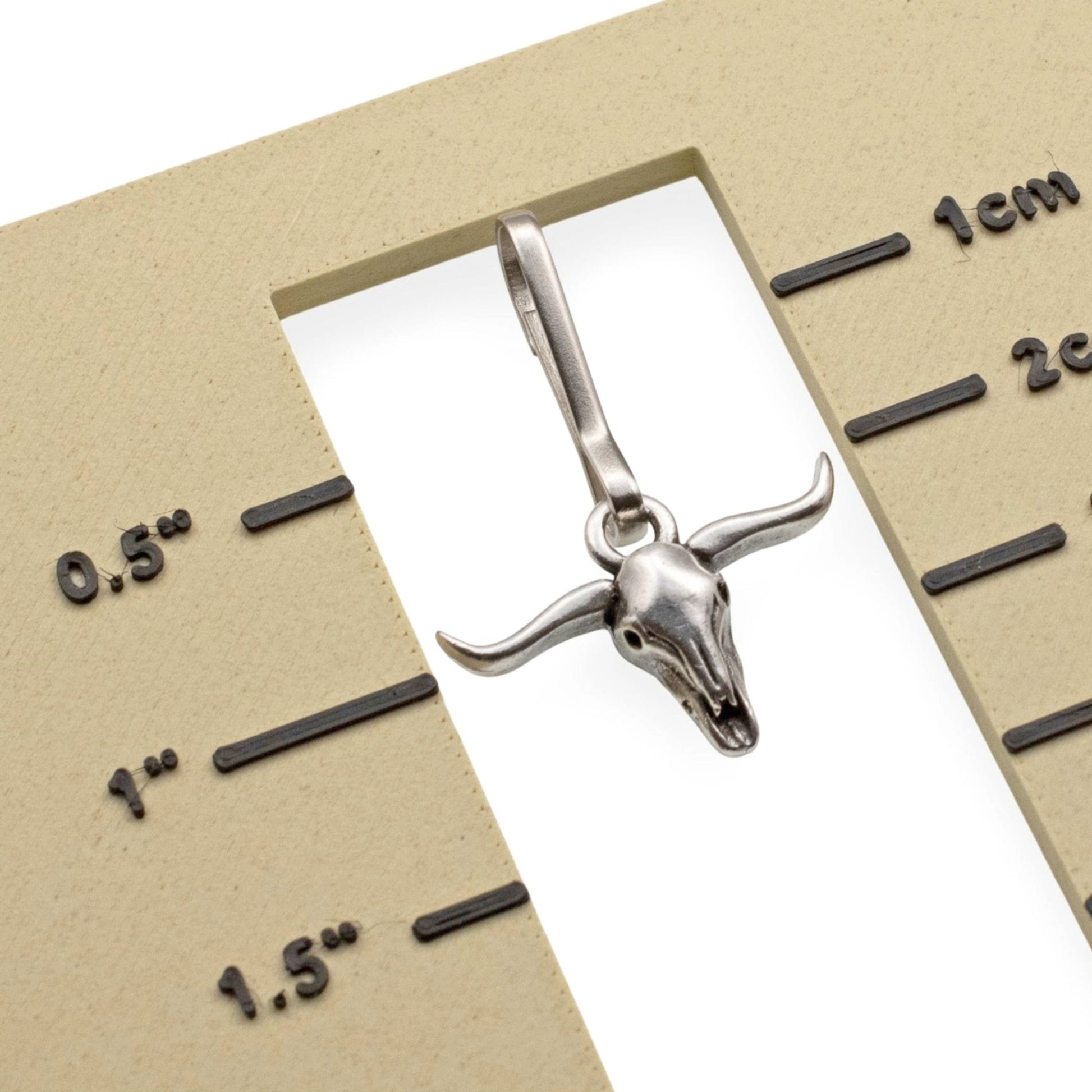 Hackberry Creek antiqued silver longhorn steer skull zipper charm with a stainless steel clasp on a measurement card.