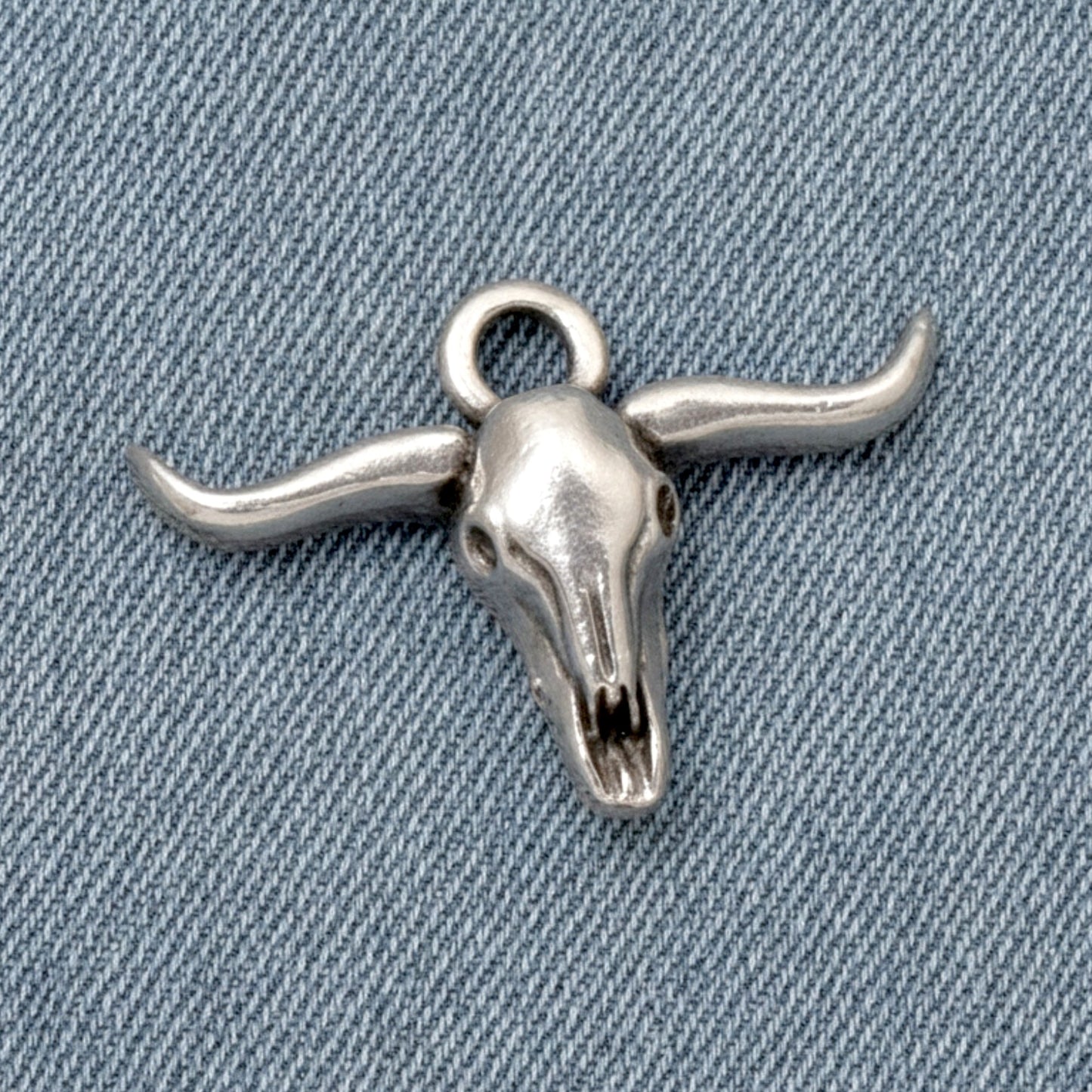 Hackberry Creek antique silver longhorn steer skull charm for southwestern boho jewelry making on denim background