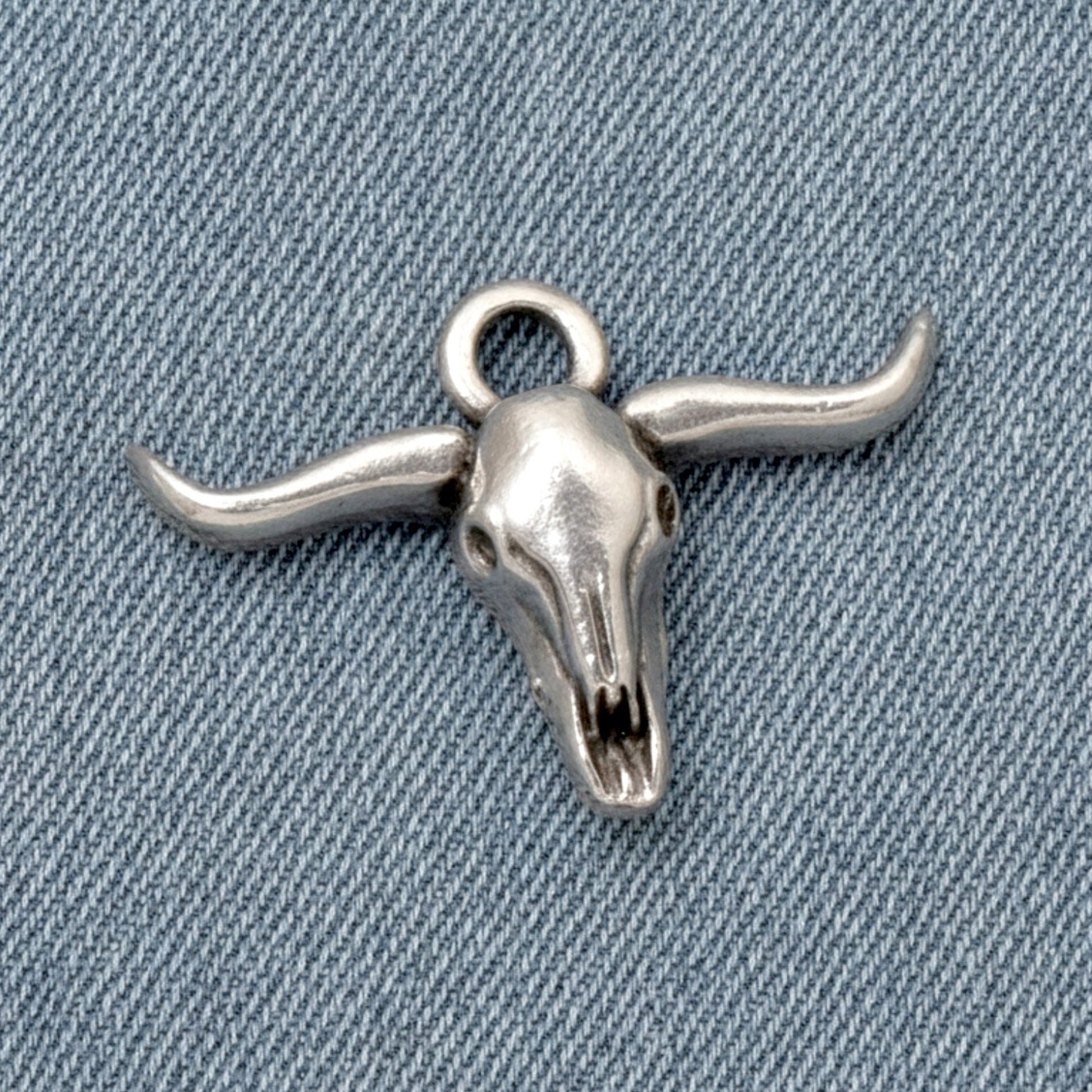 Hackberry Creek antique silver longhorn steer skull charm for southwestern boho jewelry making on denim background