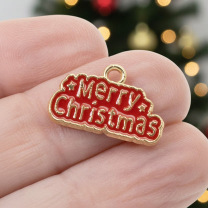 Hackberry Creek gold-plated metal alloy charm with red enamel Merry Christmas text held between fingers