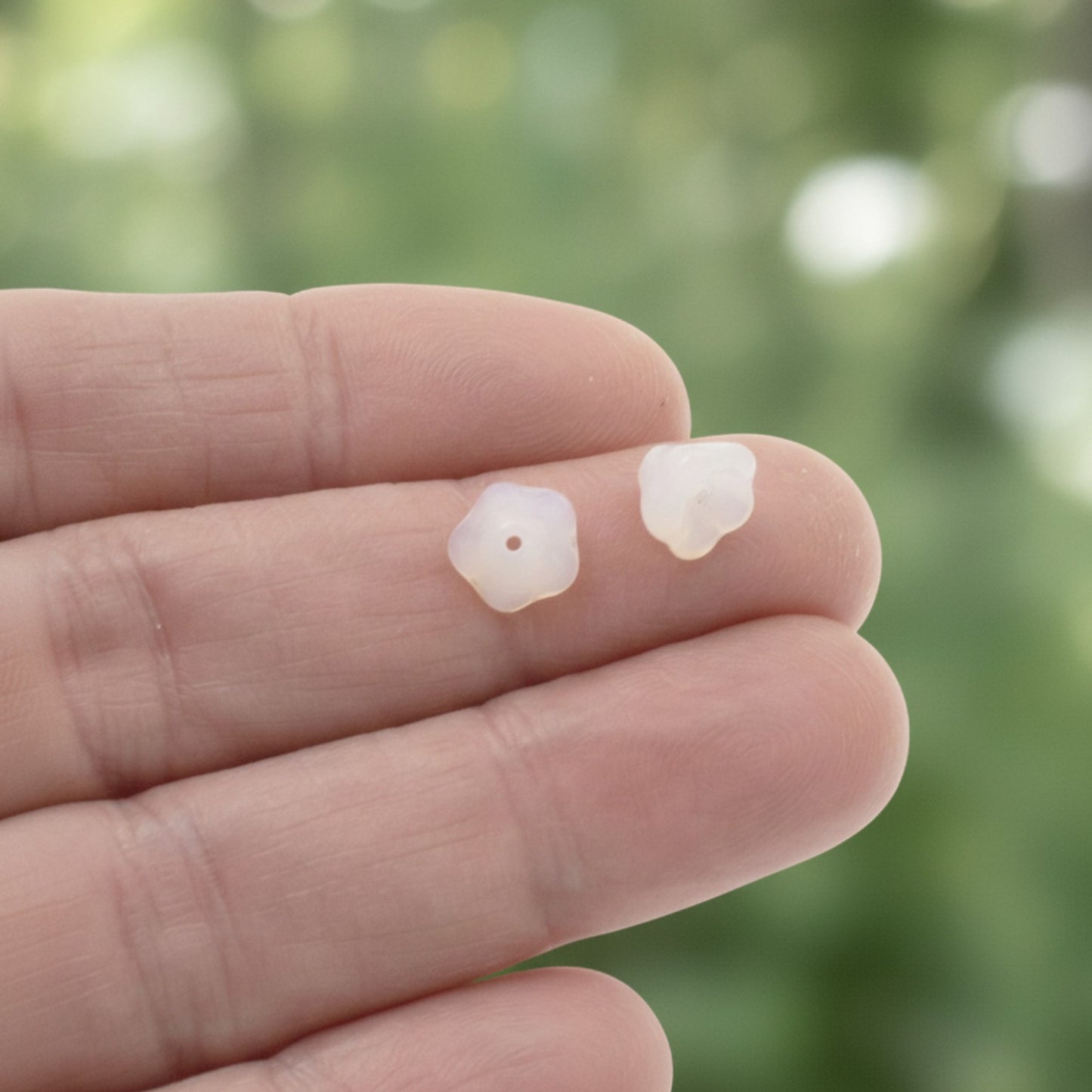 Hackberry Creek milky white Czech glass bell flower beads held on fingers for jewelry making