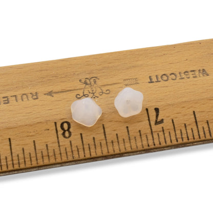 Hackberry Creek milky white Czech glass bell flower beads for jewelry making, shown next to a ruler for scale.
