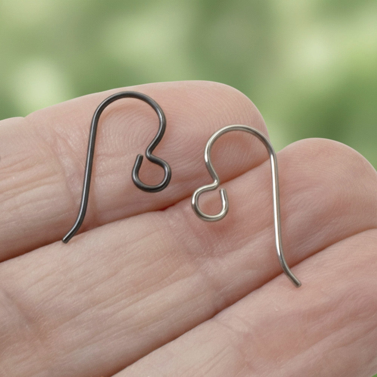 Hackberry Creek hypoallergenic niobium earring hooks in black and gray finishes held in a hand