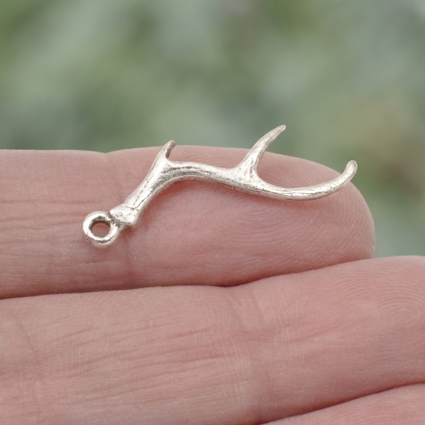 Hackberry Creek Nunn Design antique silver plated pewter antler charm held on a finger for scale