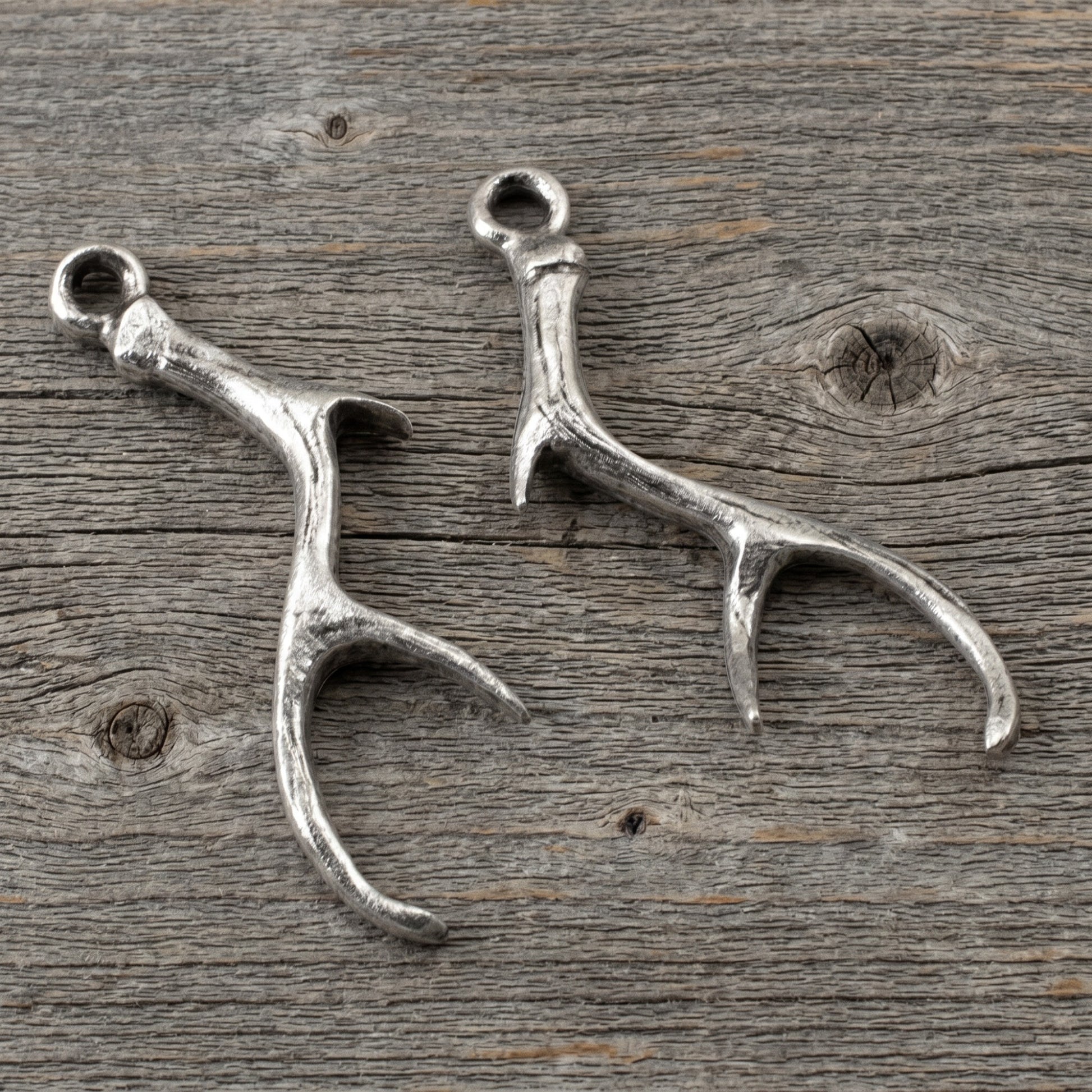 Hackberry Creek Nunn Design silver plated pewter antler charms for artisan jewelry making on a rustic wood background