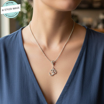 Hackberry Creek silver Om symbol charm on a ball chain necklace worn by a person in a navy blue V-neck top