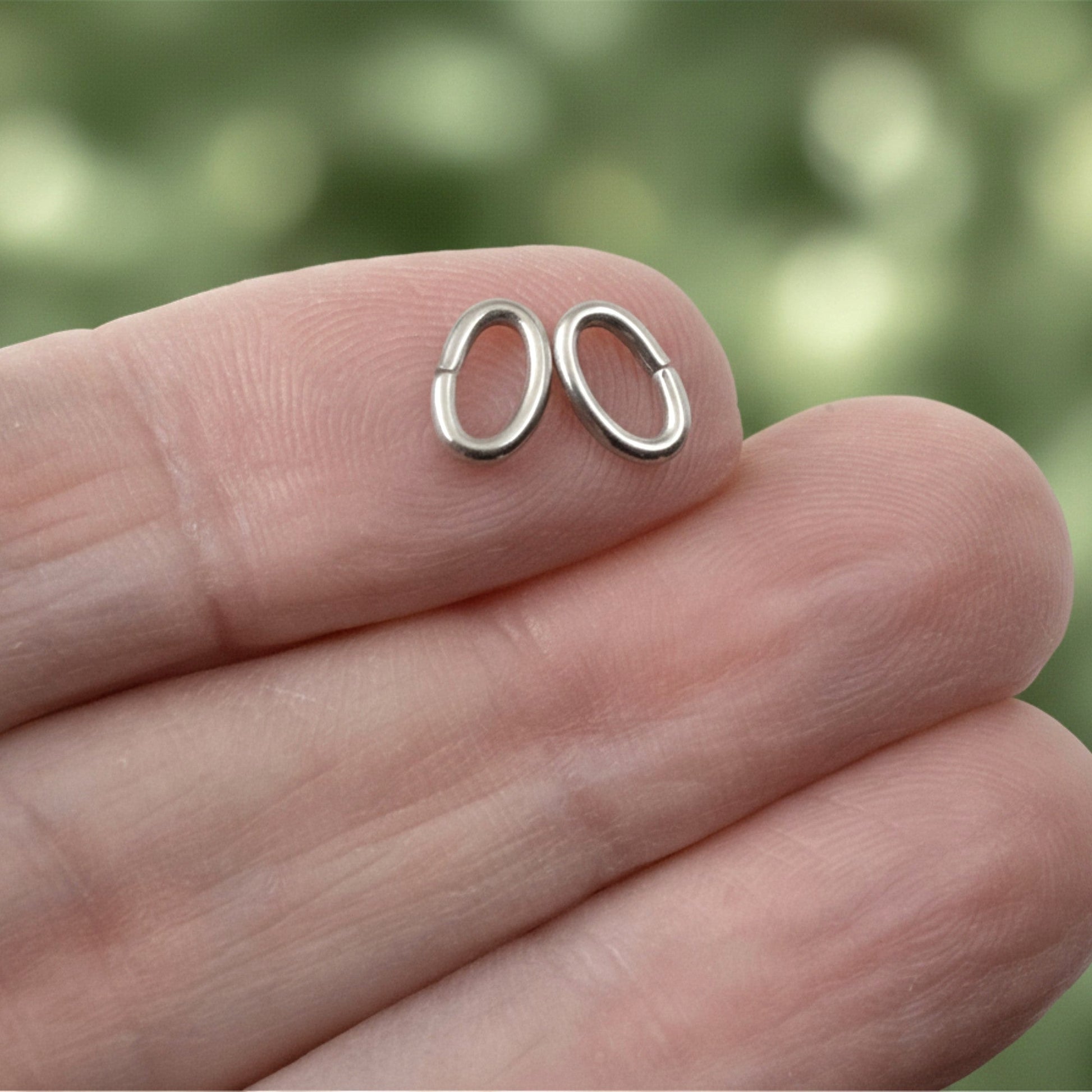 Hackberry Creek heavy duty dark silver 304 stainless steel oval jump rings held on a finger