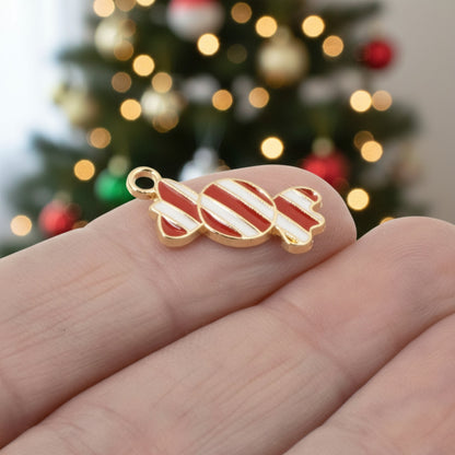 Hackberry Creek peppermint candy charm with red and white enamel stripes and gold-plated backing held in hand