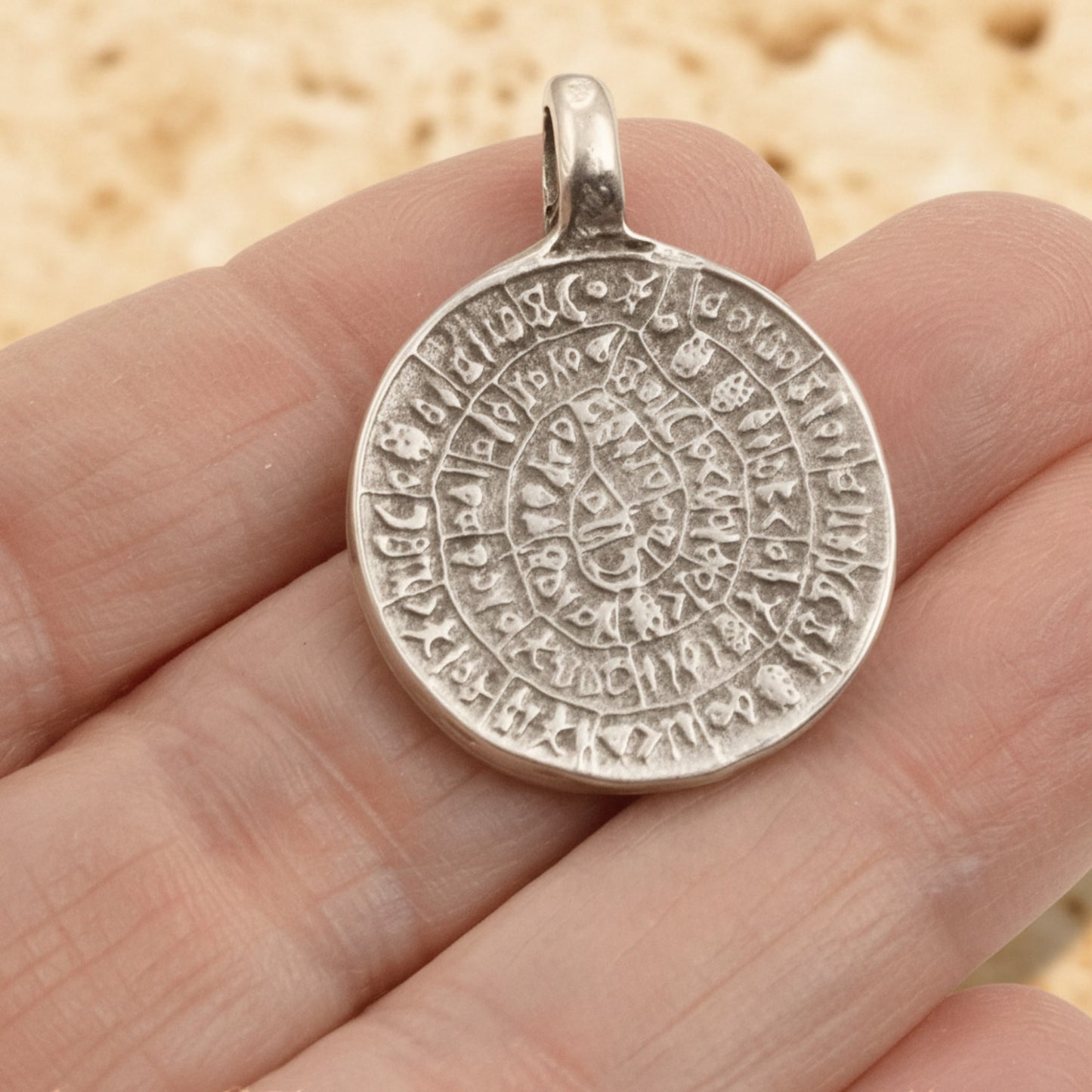 Hackberry Creek silver-plated Zamak Phaistos Disc pendant with ancient Greek spiral script, 25mm oval shape.