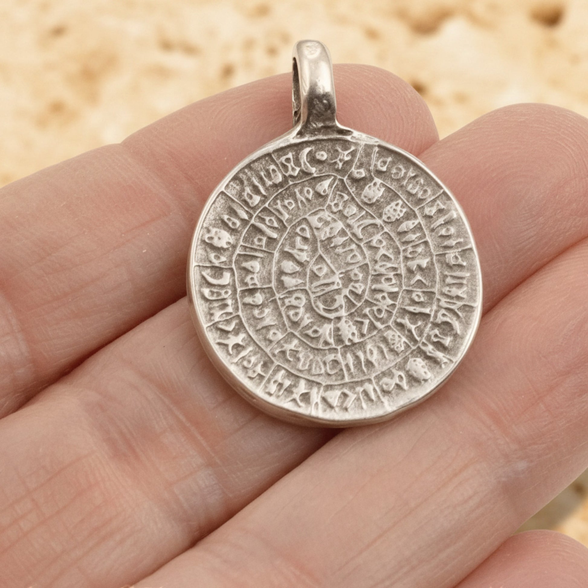 Hackberry Creek silver-plated Zamak Phaistos Disc pendant with ancient Greek spiral script, 25mm oval shape.
